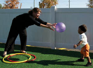 Teacher tossing a ball to a toddler